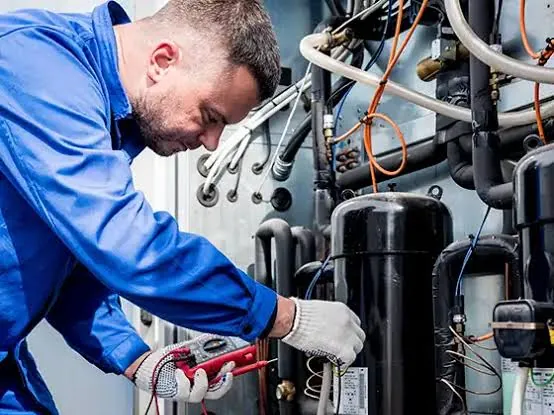 A refrigeration technician testing electrical connections on a commercial compressor unit